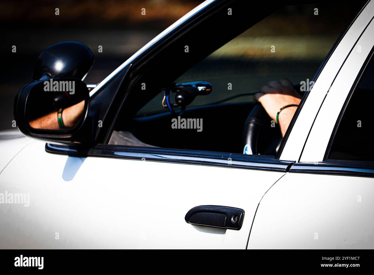 Mano sulla ruota attraverso la finestra aperta di un Interceptor P7B bianco della polizia di Crown Victoria Foto Stock Mano sulla ruota attraverso la finestra aperta di un Interceptor P7B bianco della polizia di Crown Victoria Foto Stock