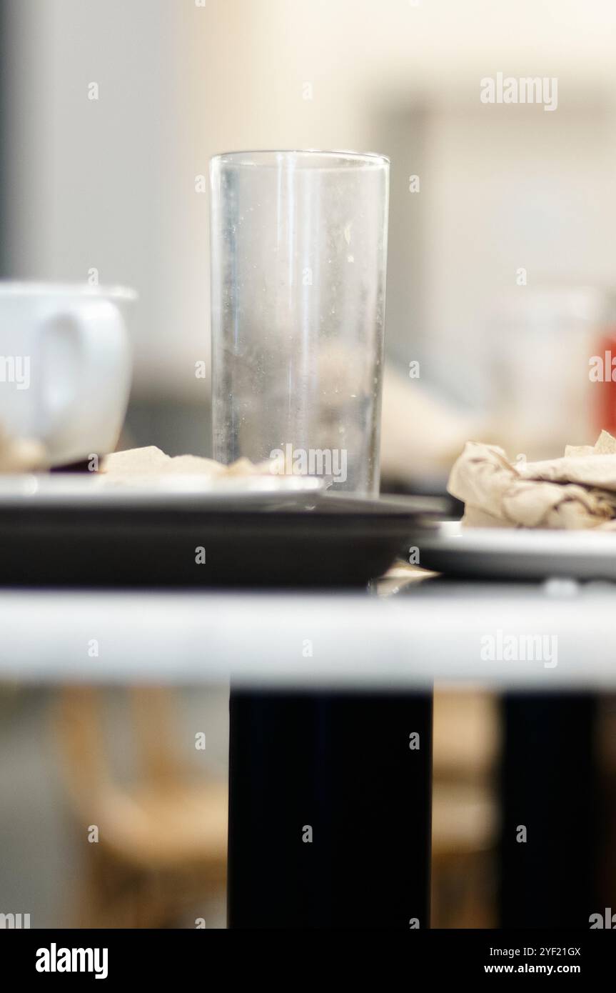 Tazza e bicchiere sporchi in modo selettivo accanto ad alcuni tovaglioli rugosi marroni. Foto Stock