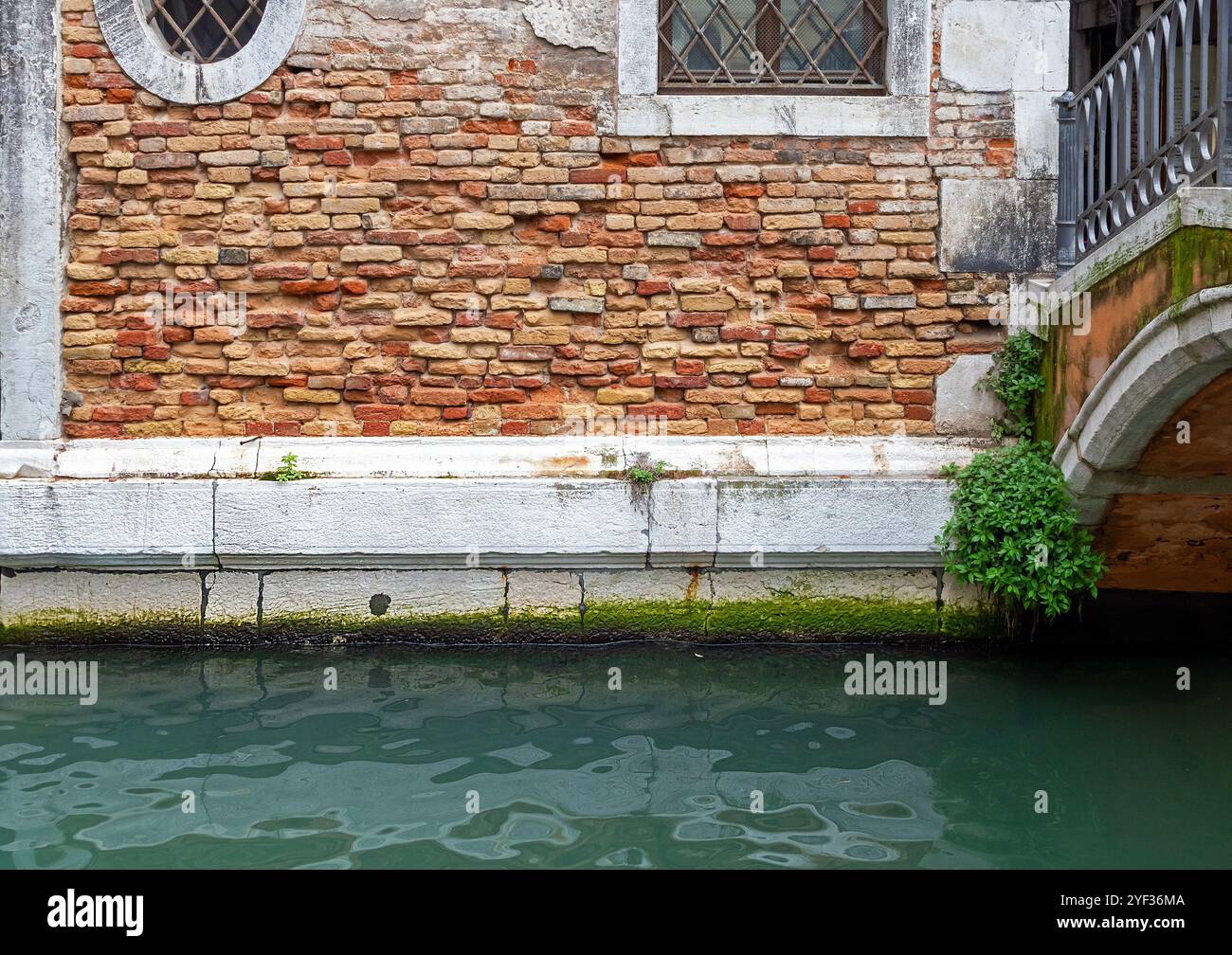 Vecchia casa con facciata murale in mattoni e ponte sul lato del canale di Venezia Foto Stock