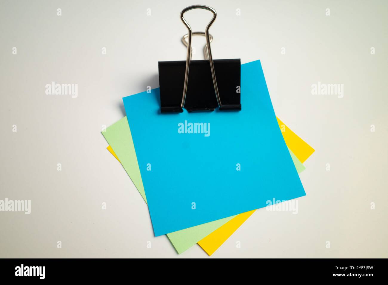 Clip per rilegatura che contiene più fogli di carta colorati impilati insieme Foto Stock