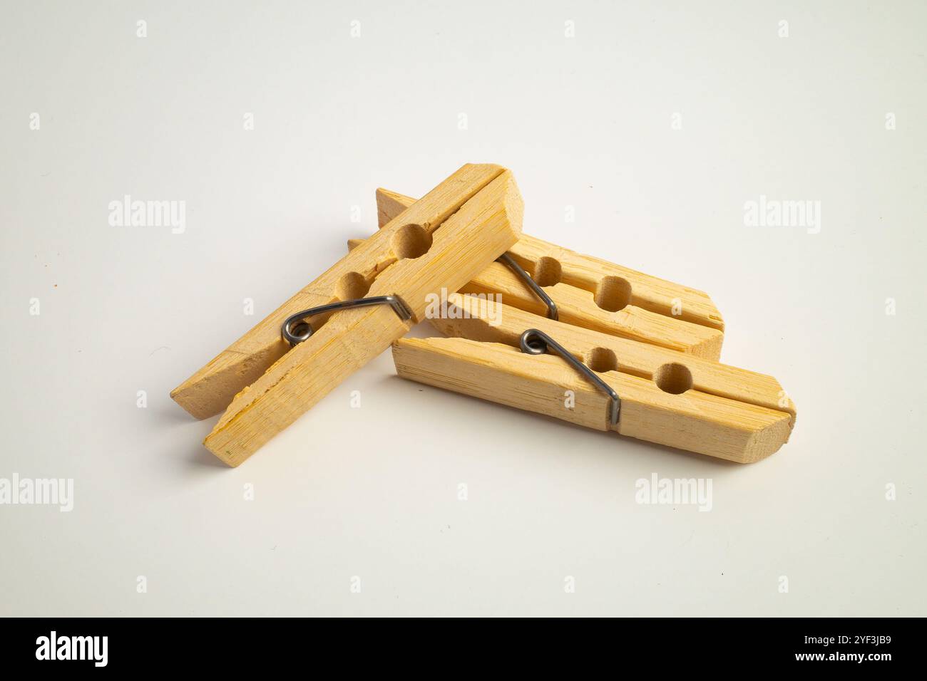 clothespins di legno impilati insieme su un semplice sfondo bianco Foto Stock