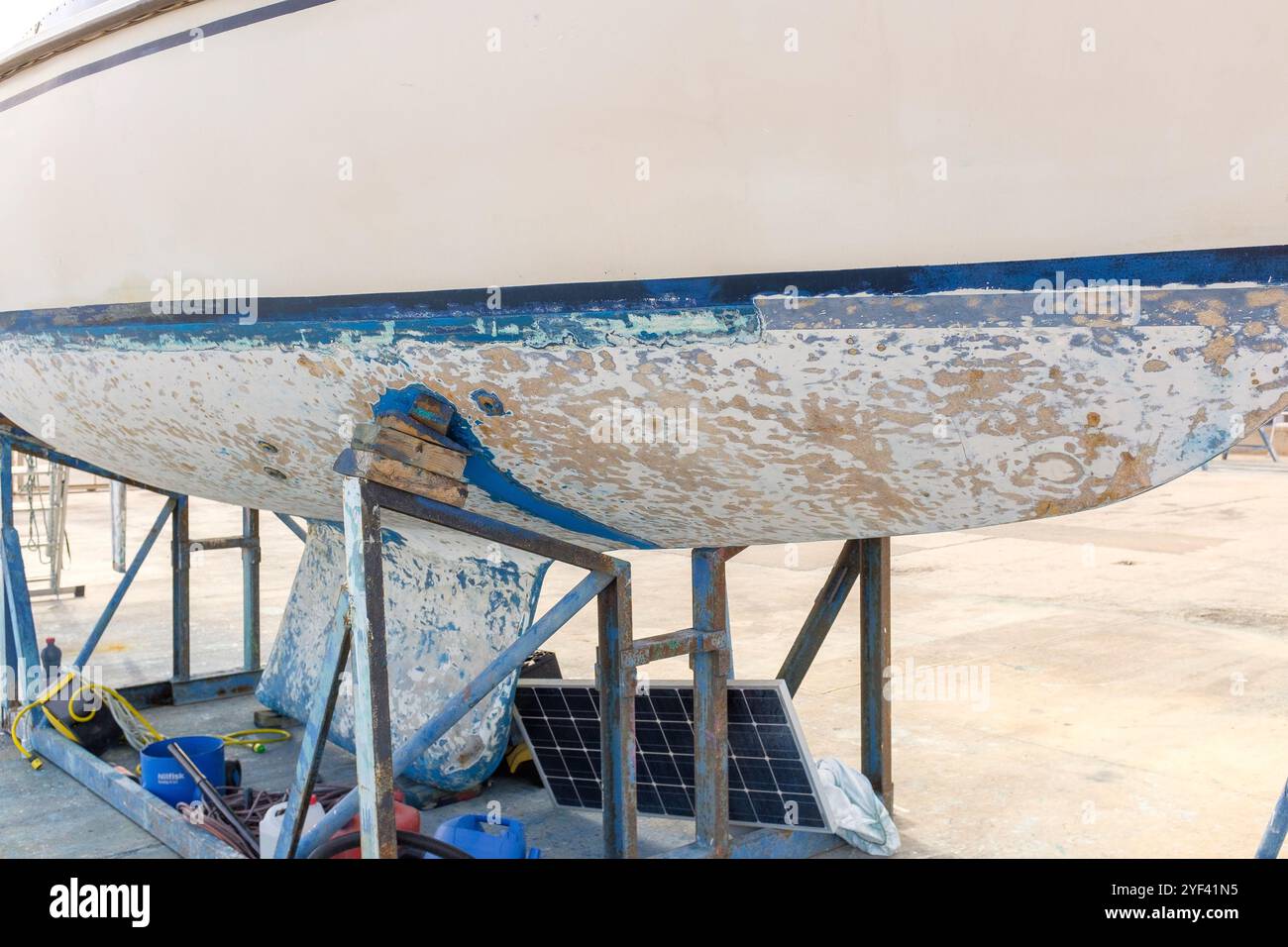 Scafo di un piccolo yacht sulla terraferma in fase di pulizia e che necessita di riverniciatura Foto Stock
