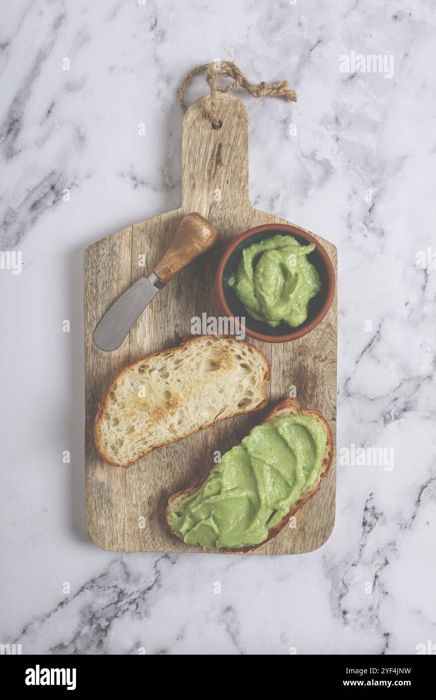 Ciabatta con pasta all'avocado, colazione, su un tagliere, vista dall'alto, fatti in casa, niente persone Foto Stock