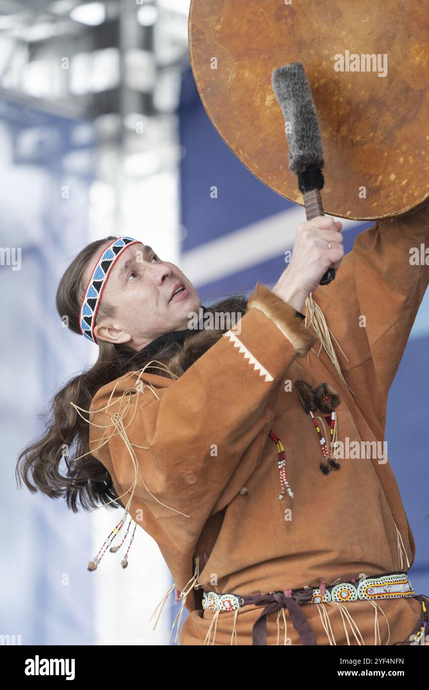 Ballerino maschile in abiti nazionali gli aborigeni esprimono ballando con il tamburello. Concerto Koryak Dance Ensemble Mengo durante lo sci alpino russo Foto Stock