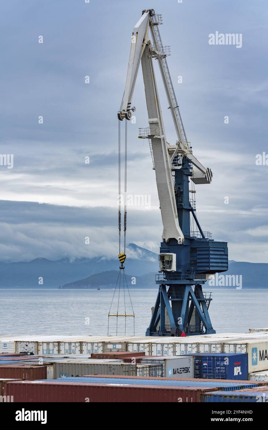 Gru a portale portuale e molti container per la spedizione di stoccaggio marittimo presso il terminal del porto marittimo sulla costa dell'Oceano Pacifico. Petropavlovsk-Kamchatsky City, Kam Foto Stock