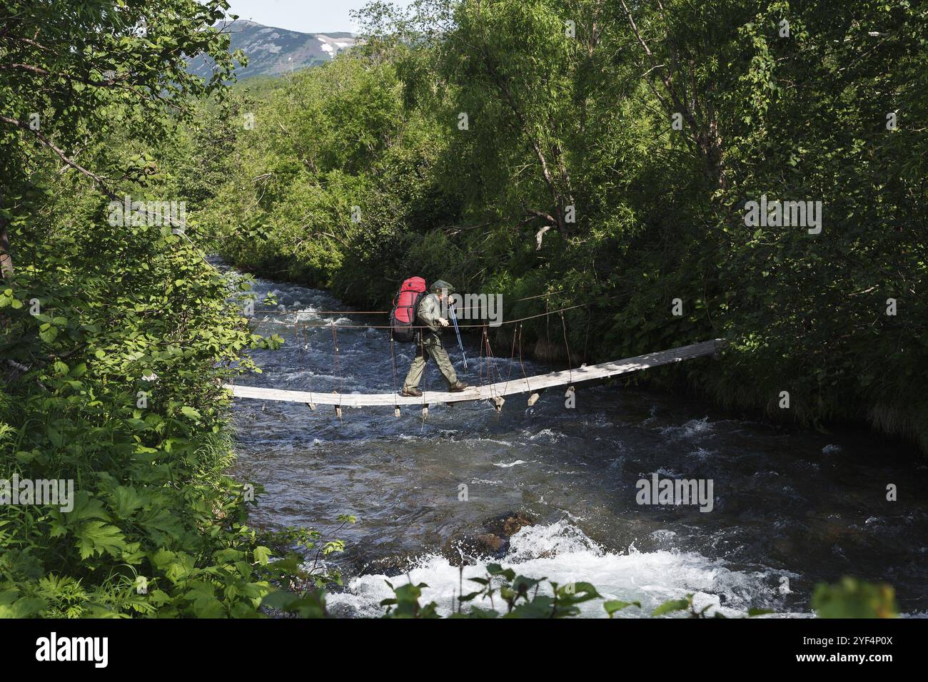 PENISOLA DI KAMCHATKA, RUSSIA, 11 giugno 2014: Escursione estiva a Kamchatka, turista donna e viaggiatrice con zaino dietro le spalle che attraversa la montagna Foto Stock