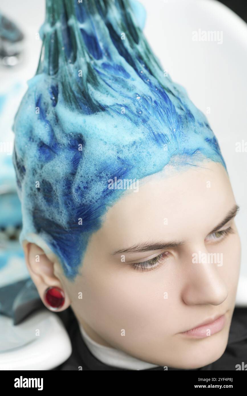 Testa di una giovane donna con i capelli blu mentre si lava la testa in un salone di bellezza professionale dopo aver tinto i capelli di zaffiro Foto Stock