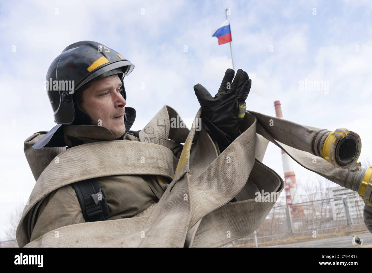 PETROPAVLOVSK CITY, PENISOLA DI KAMCHATKA, RUSSIA, APR 19, 2019: Pompiere-soccorritore Emercom della Russia raccoglie lunghe manichette di fuoco sulle mani. Vigili del fuoco AN Foto Stock