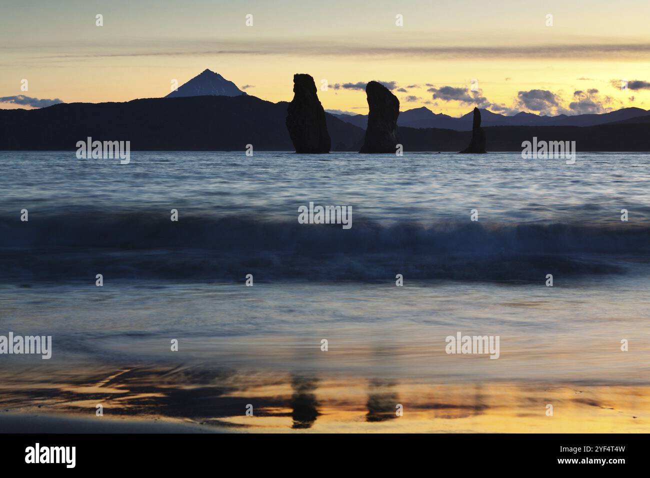 Uno splendido tramonto, pittoresca vista delle tre rocce dei Fratelli nella Baia di Avacha e del Vulcano Viluchinsky all'orizzonte. Oceano Pacifico, Estremo Oriente russo, Ka Foto Stock