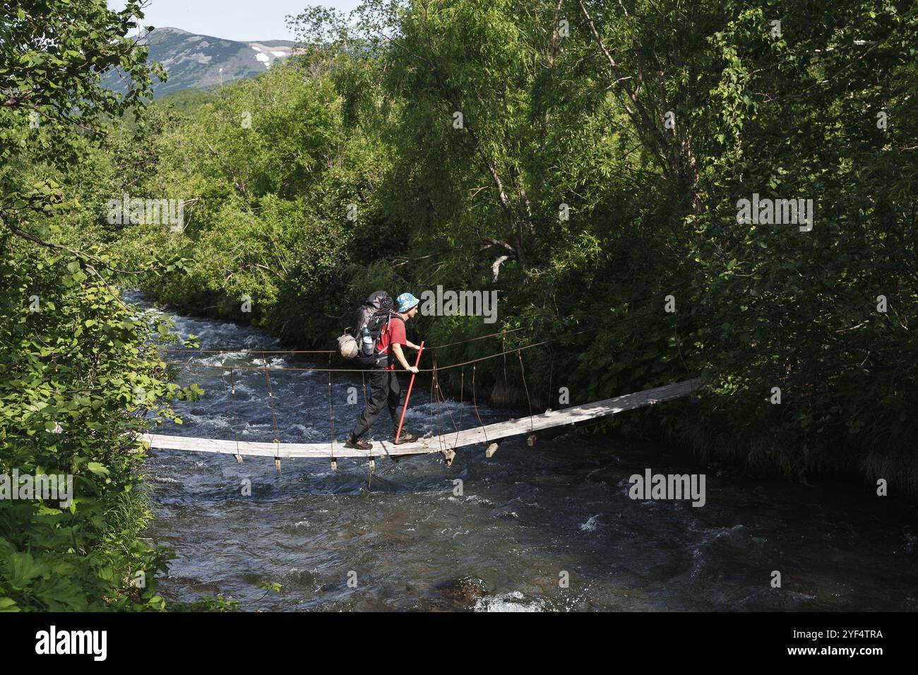 PENISOLA DI KAMCHATKA, ESTREMO ORIENTE RUSSO, 11 LUGLIO 2014: Escursione estiva a Kamchatka, turista con zaino dietro le spalle che attraversa il fiume di montagna o Foto Stock
