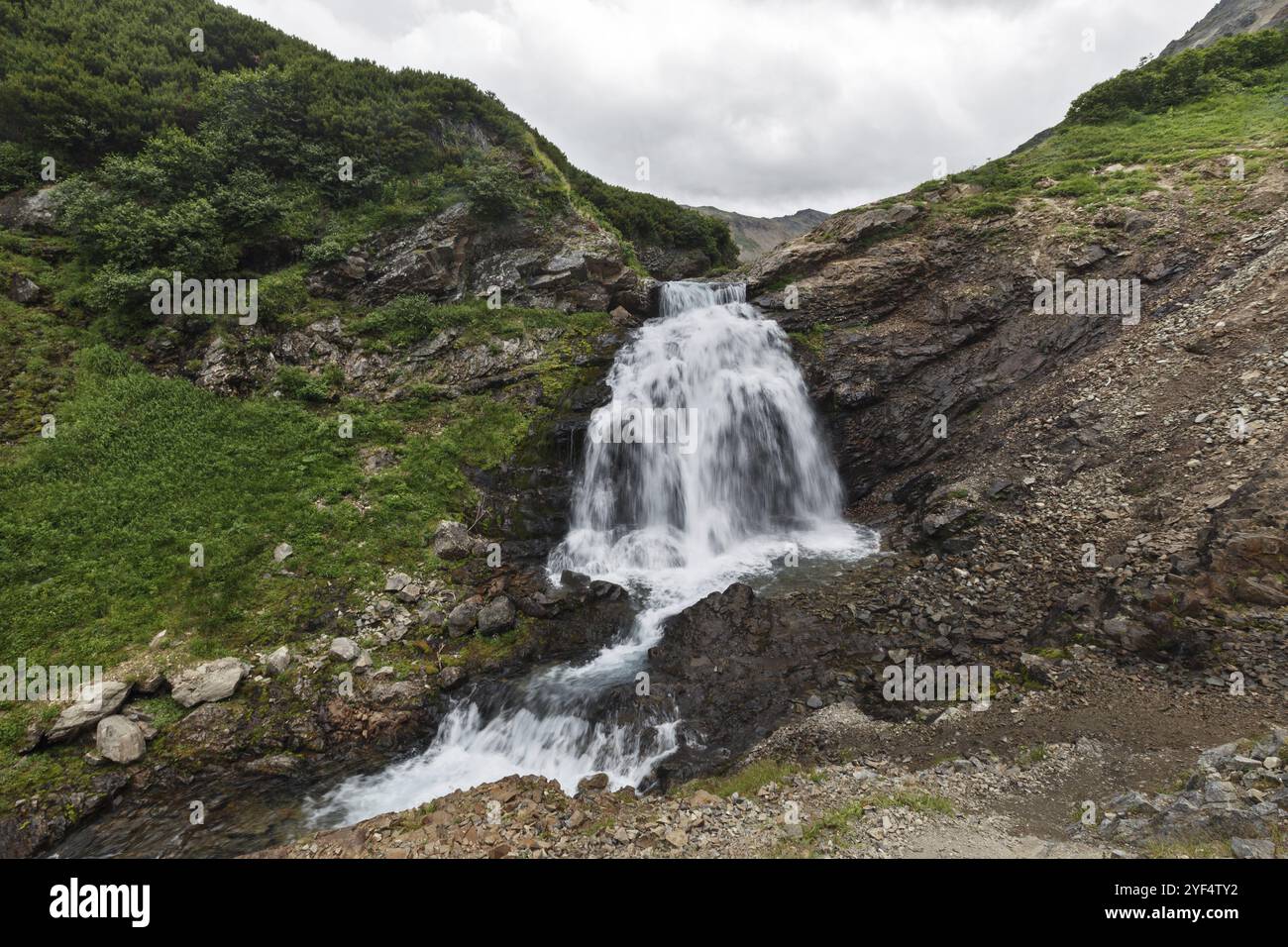 Splendido paesaggio montano di Kamchatka: Vista estiva della pittoresca cascata nella catena montuosa Vachkazhets. Eurasia, Russia, Estremo Oriente, Kamchatka PE Foto Stock