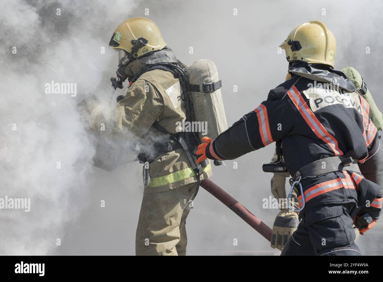 I vigili del fuoco spengono il fuoco dal tubo antincendio, utilizzando un cilindro in schiuma di acqua antincendio con schiuma meccanica ad aria. Giorno dei pompieri di festa professionale. P. Foto Stock