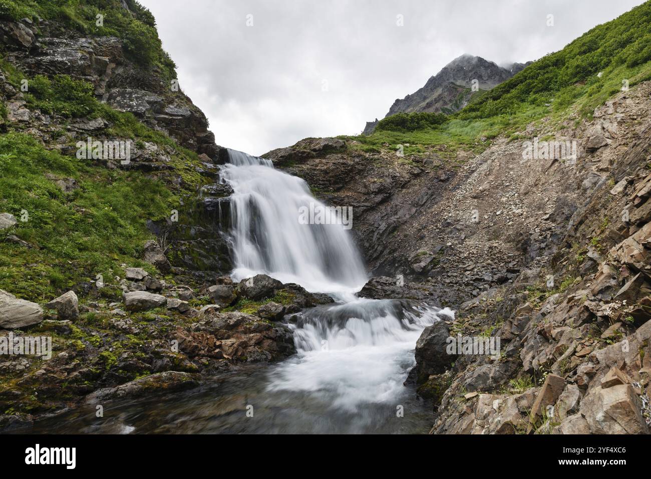 Paesaggio montano estivo di Kamchatka: Splendida vista della pittoresca cascata nella catena montuosa Vachkazhets. Eurasia, Estremo Oriente russo, Kamchatka PE Foto Stock