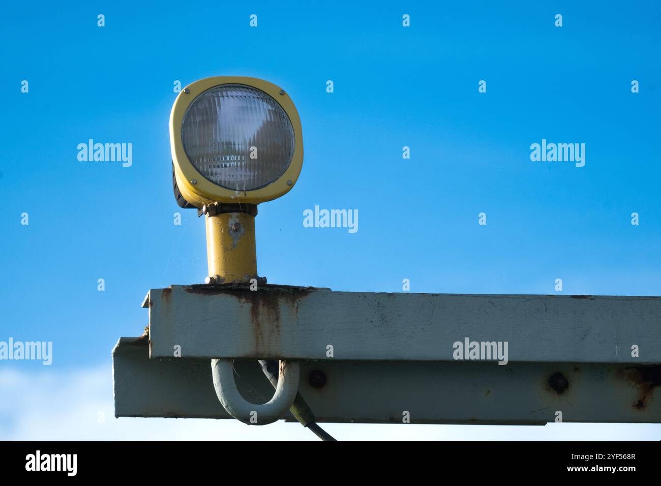 Primo piano di una singola luce di avvicinamento aeroportuale su un gantry grigio arrugginito contro un cielo blu Foto Stock