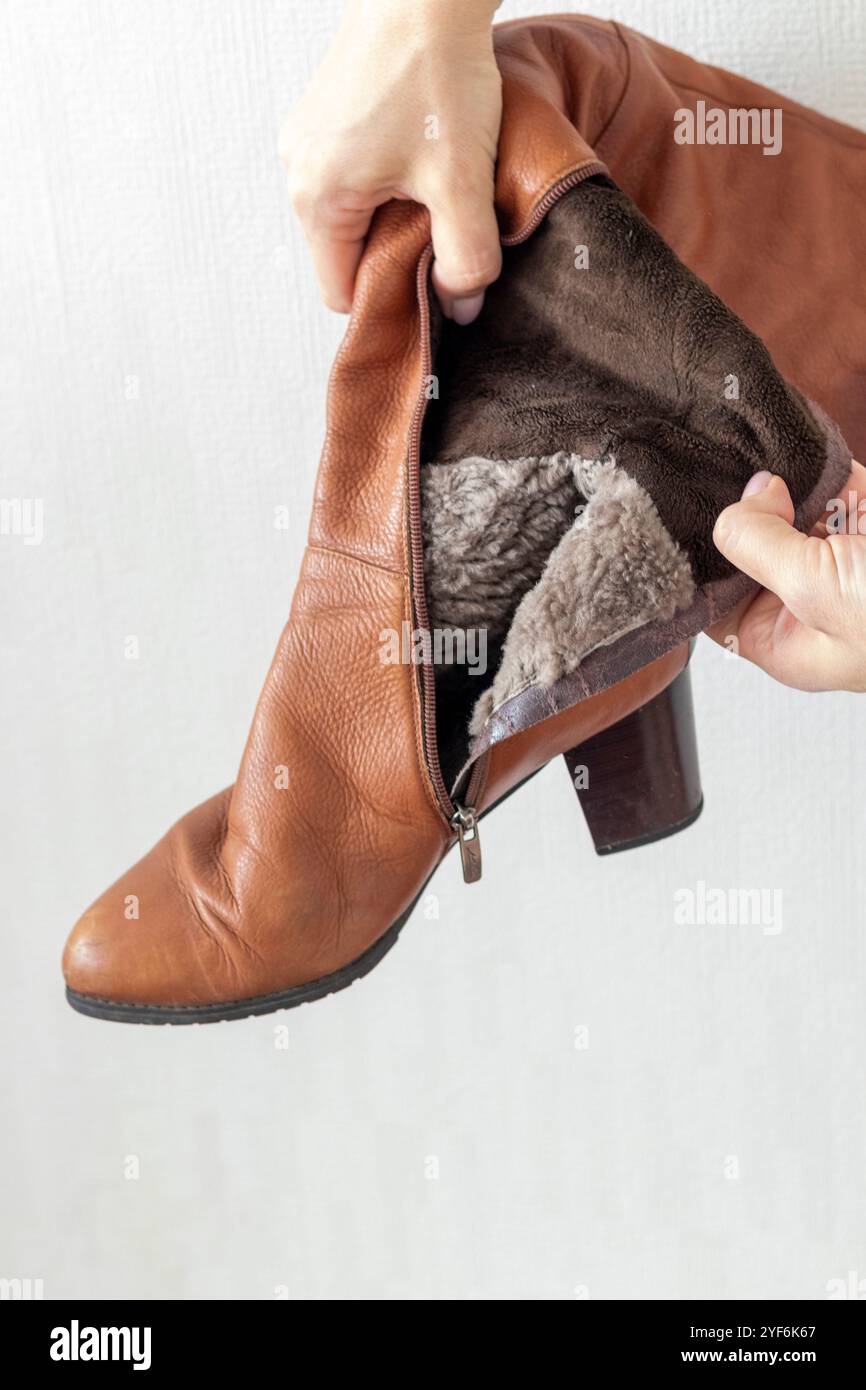 Donna che mostra pelliccia all'interno di stivali in pelle Foto Stock