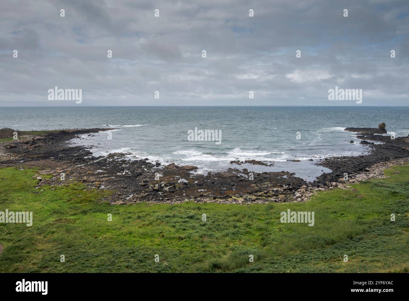 Vista di una spiaggia di ciottoli di basalto nero lungo la costa di Antrim, vicino al Selciato del gigante, nell'Irlanda del Nord Foto Stock