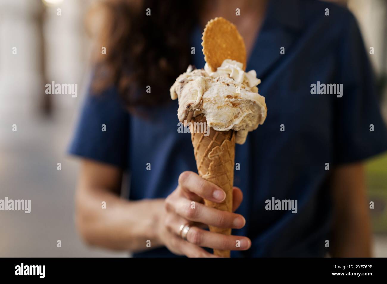 Donna in piedi per strada con un cono di cialda con pistacchio e gelato Stracciatella, panna montata e biscotti, Costiera Amalfitana, Italia Foto Stock