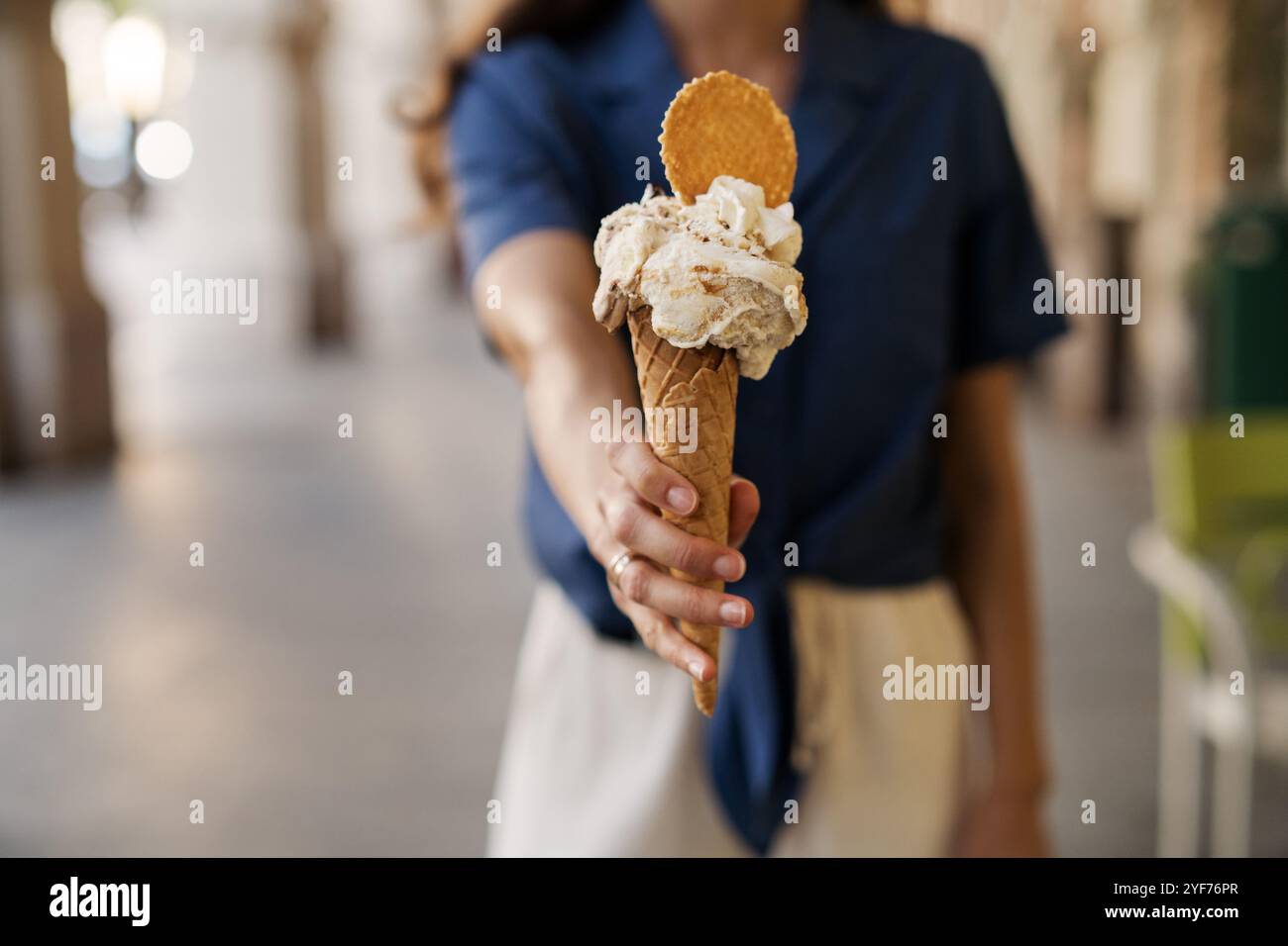 Donna in piedi per strada con un cono di cialda con pistacchio e gelato Stracciatella, panna montata e biscotti, Costiera Amalfitana, Italia Foto Stock