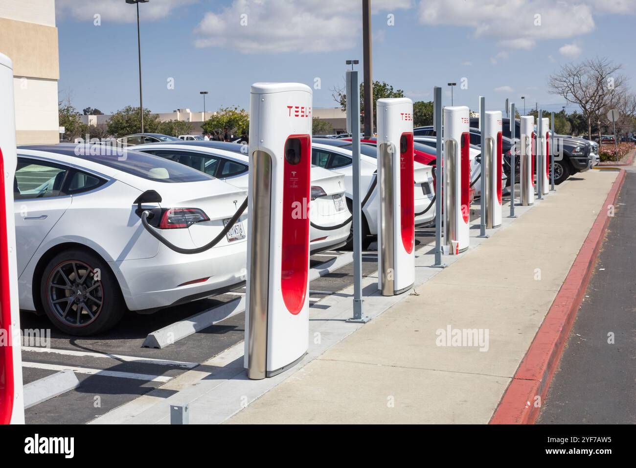 Fountain Valley, California, Stati Uniti - 03-24-19: Vista di diverse auto Tesla parcheggiate e ricaricate presso una stazione locale Tesla Supercharger. Foto Stock