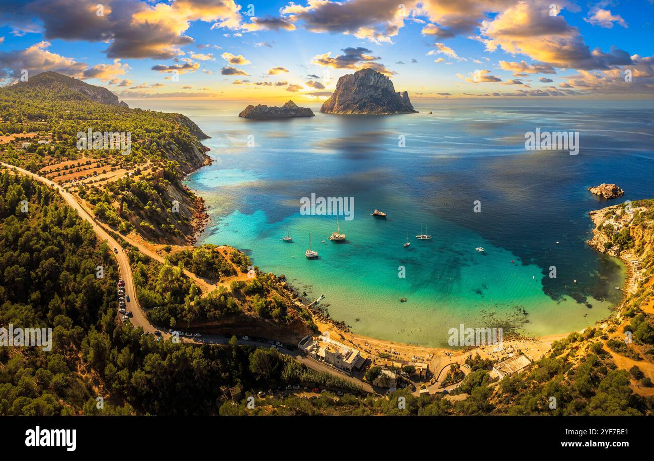 Vista aerea della spiaggia di Cala d'Hort a Ibiza, con l'iconica roccia di es Vedrà, le acque turchesi e la panoramica costa mediterranea. Foto Stock