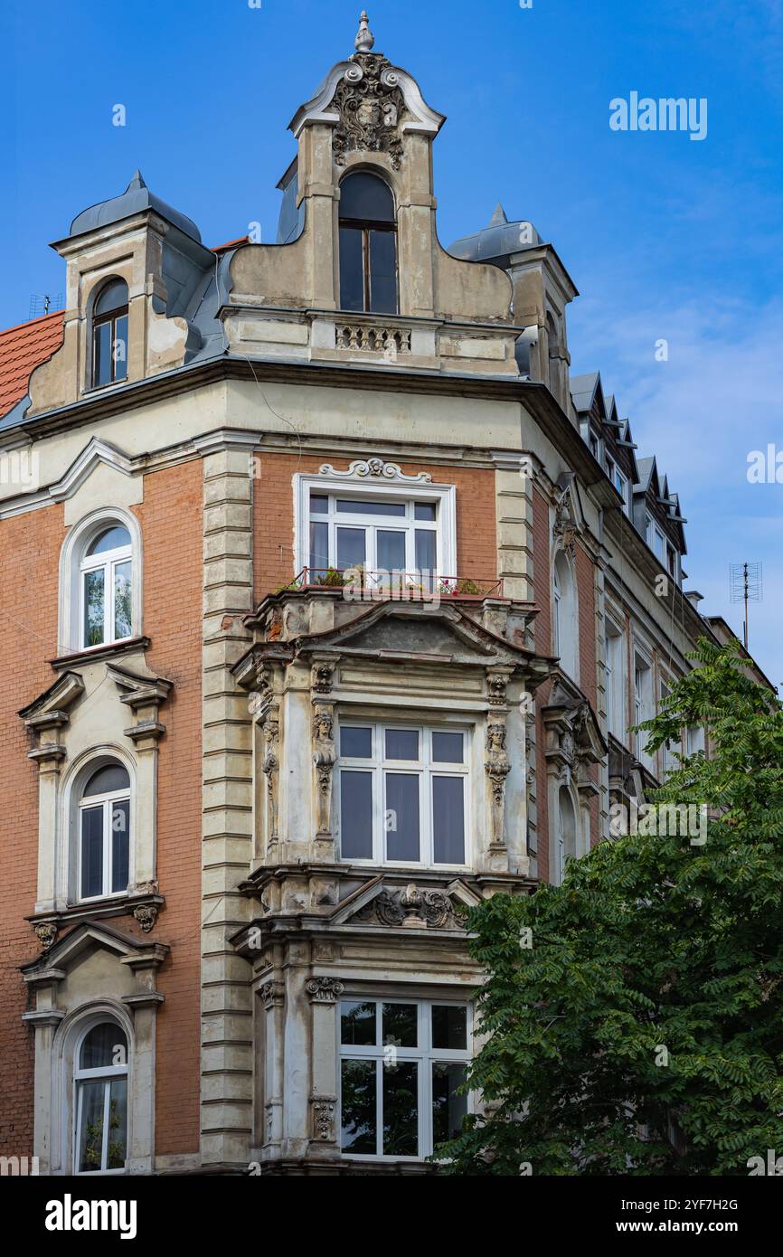 Facciata di un edificio storico europeo con intricati dettagli architettonici, finestre d'epoca e un design d'angolo splendidamente conservato sotto un cielo blu Foto Stock