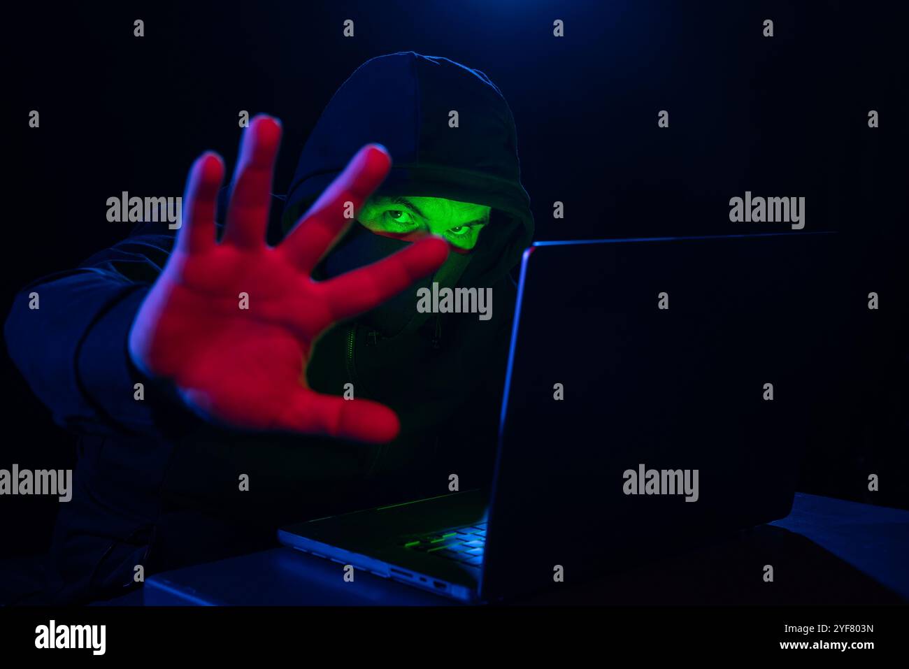 Computer hacker in felpa con cappuccio. Faccia oscura oscurata. Attacco di hacker, software infetto da virus, Dark Web e concetto di sicurezza informatica . Foto Stock