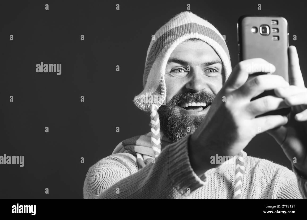 Tempo di selfie. Uomo sorridente che fa autoritratti sullo smartphone. Hobby fotografo. Bell'uomo fa selfie. Uomo barbuto felice con cappello divertente che prende sel Foto Stock