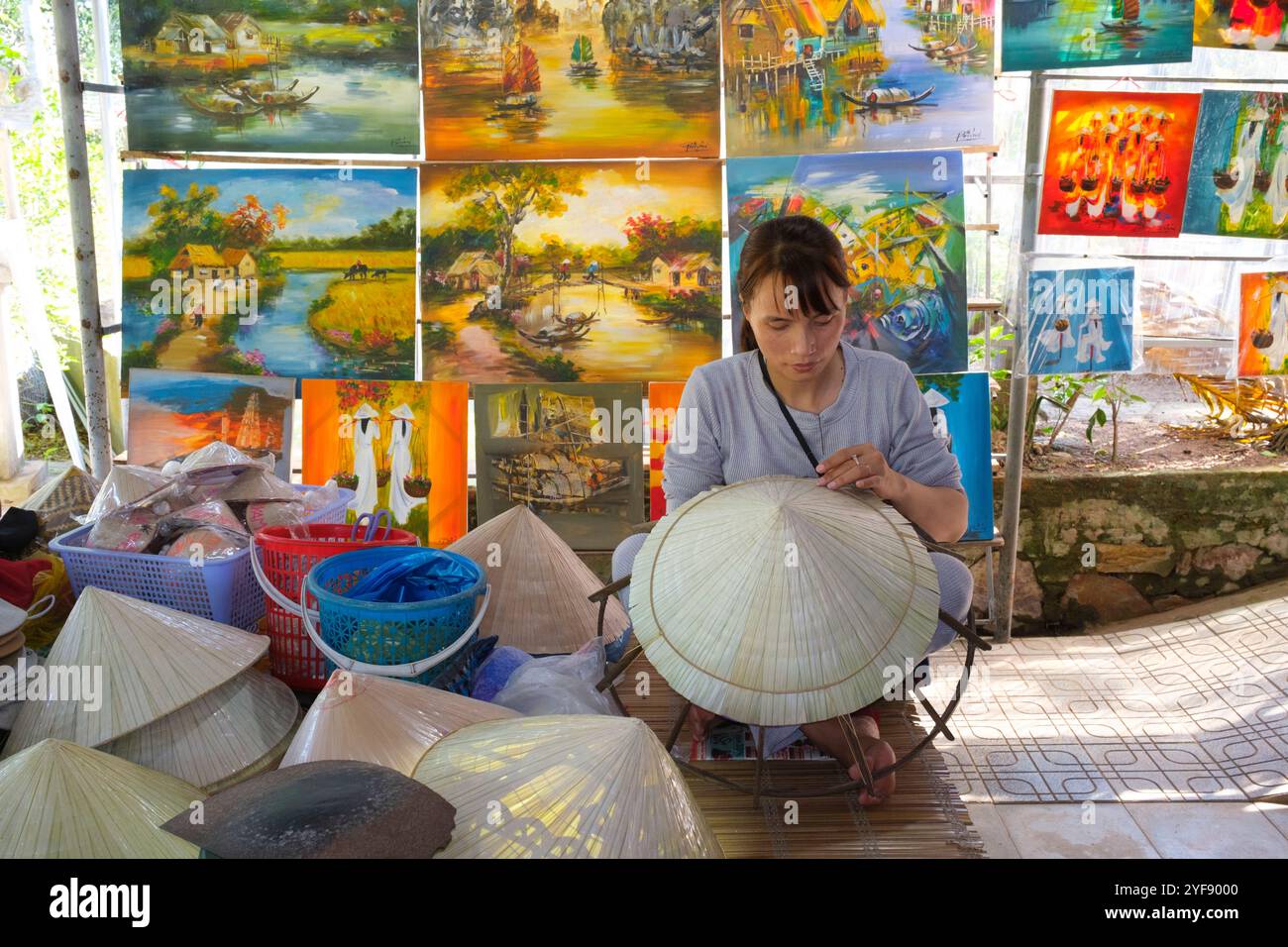 Vietnam: Un produttore non la (cappello conico vietnamita), Thuy Xuan Incense-making Village, Hue. L'onnipresente non la (cappello conico) color crema protegge gli agricoltori dal sole tropicale e dalle piogge monsoniche come un ombrellone mobile. Il cappello è fatto di foglie di palma latania tessute circa un lath di bambù. Oggi, molte più donne che uomini indossano l'emblematico copricapo. Foto Stock