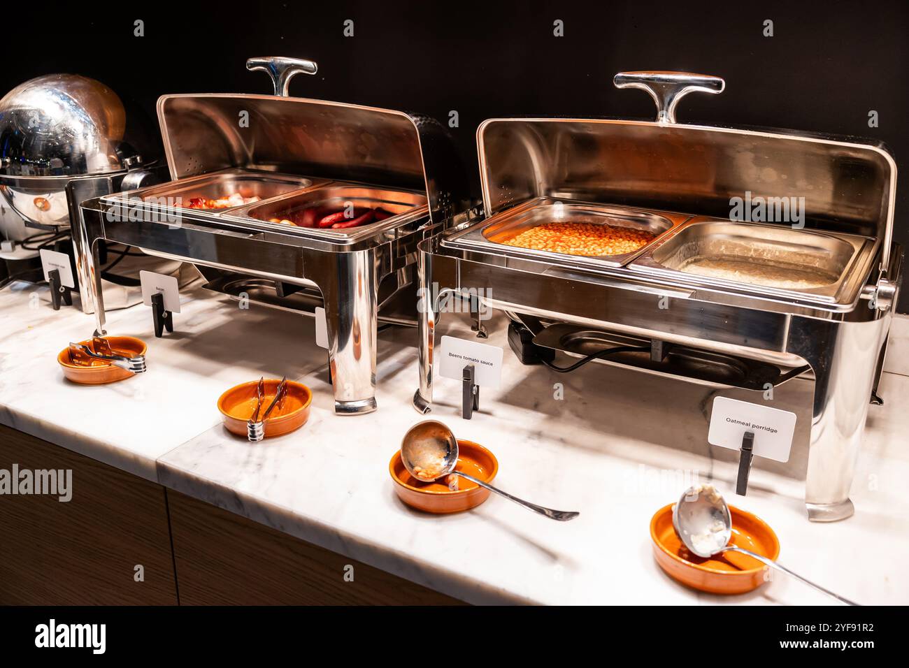 Colazione tradizionale con pancetta, salsicce e fagioli nei vassoi riscaldati Foto Stock