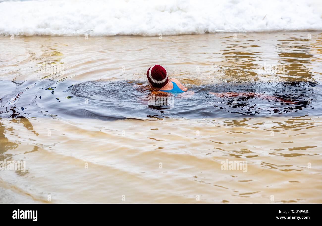 Nuotate nelle acque ghiacciate, indossando una cuffia vibrante, affrontate il freddo per nuotare in inverno Foto Stock
