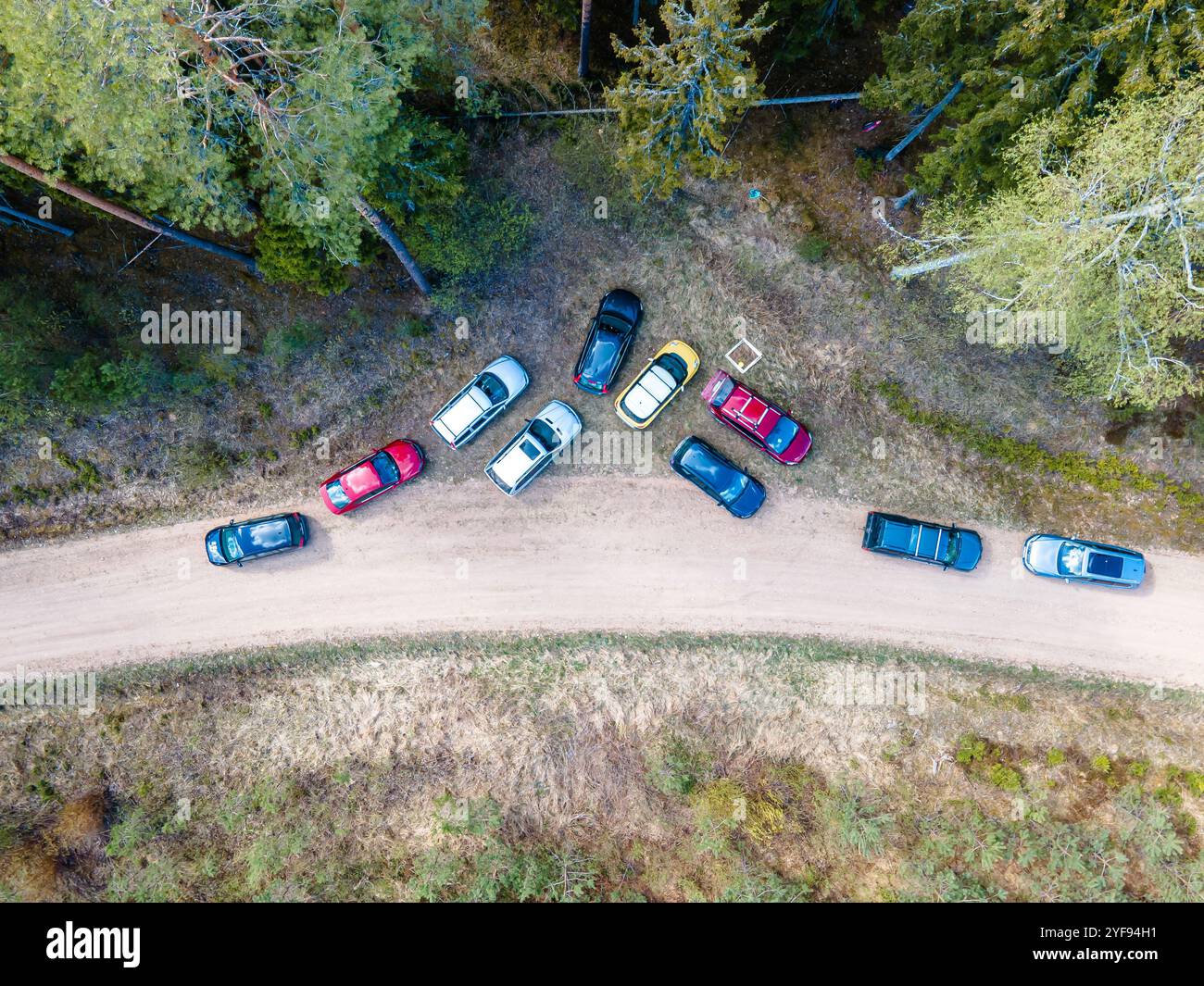 vista aerea delle auto parcheggiate in modo casuale su una strada sterrata circondata dalla foresta - una prospettiva unica di parcheggio all'aperto Foto Stock