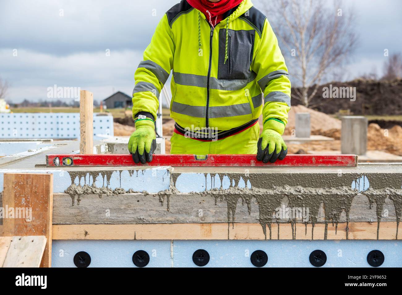 Operaio edile che utilizza la livella su forme di calcestruzzo isolate presso il cantiere edile Foto Stock