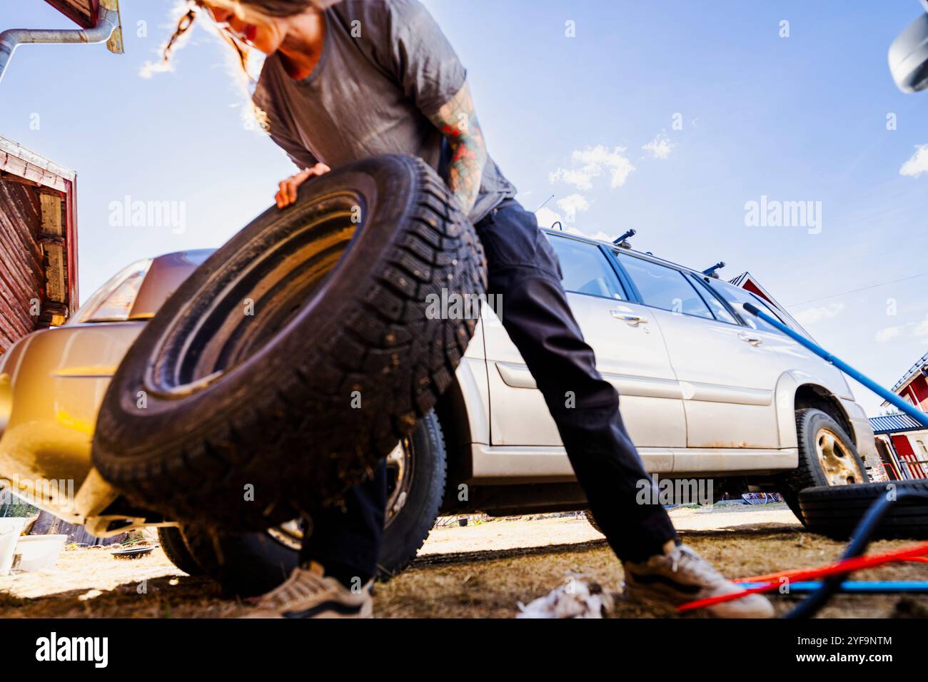 Pneumatico per il trasporto meccanico femminile per la riparazione nelle giornate di sole Foto Stock