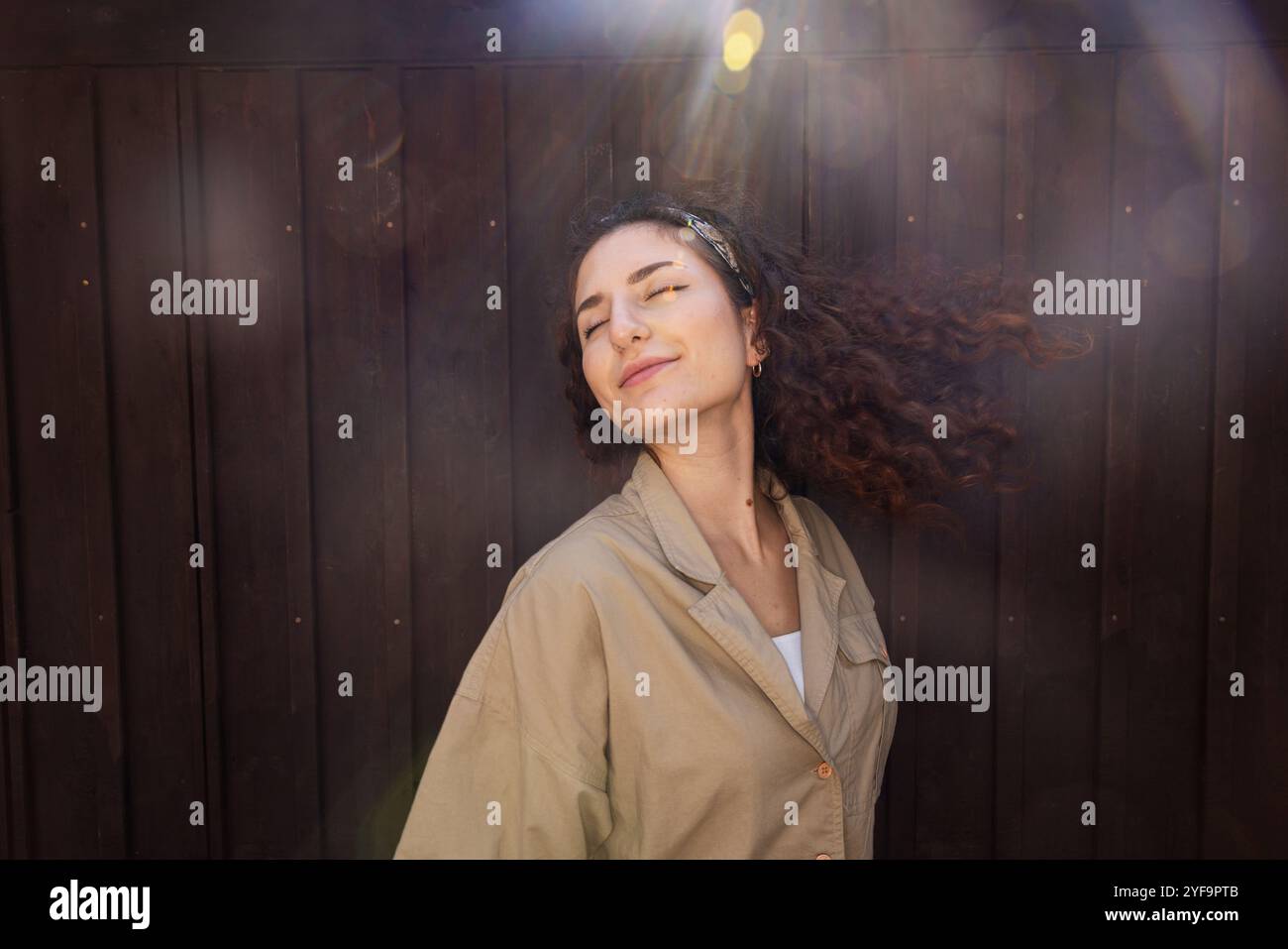 Bella giovane donna con capelli duri contro le pareti durante il giorno di sole Foto Stock