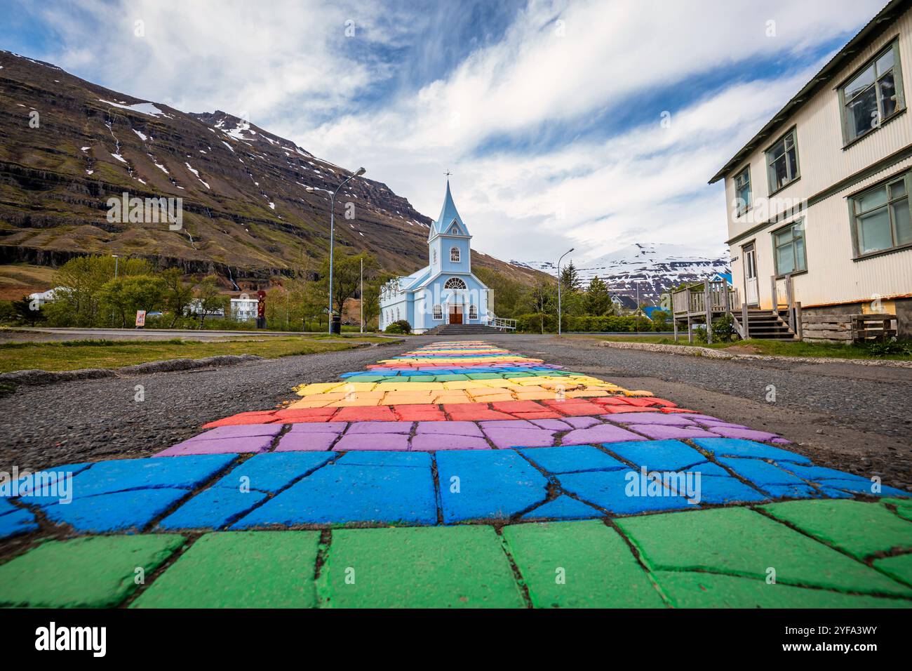 La famosa strada arcobaleno a Seydisfjordur con edifici islandesi intorno mostrano opere d'arte dipinte sulle pareti. Città di Seydisfjordur in Islanda. Foto Stock