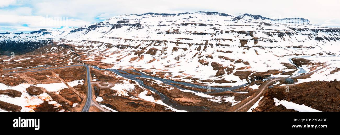 Splendida vista aerea del paesaggio spettacolare dell'Islanda, con montagne innevate e un fiume che si snoda attraverso una vallata aspra. Foto Stock