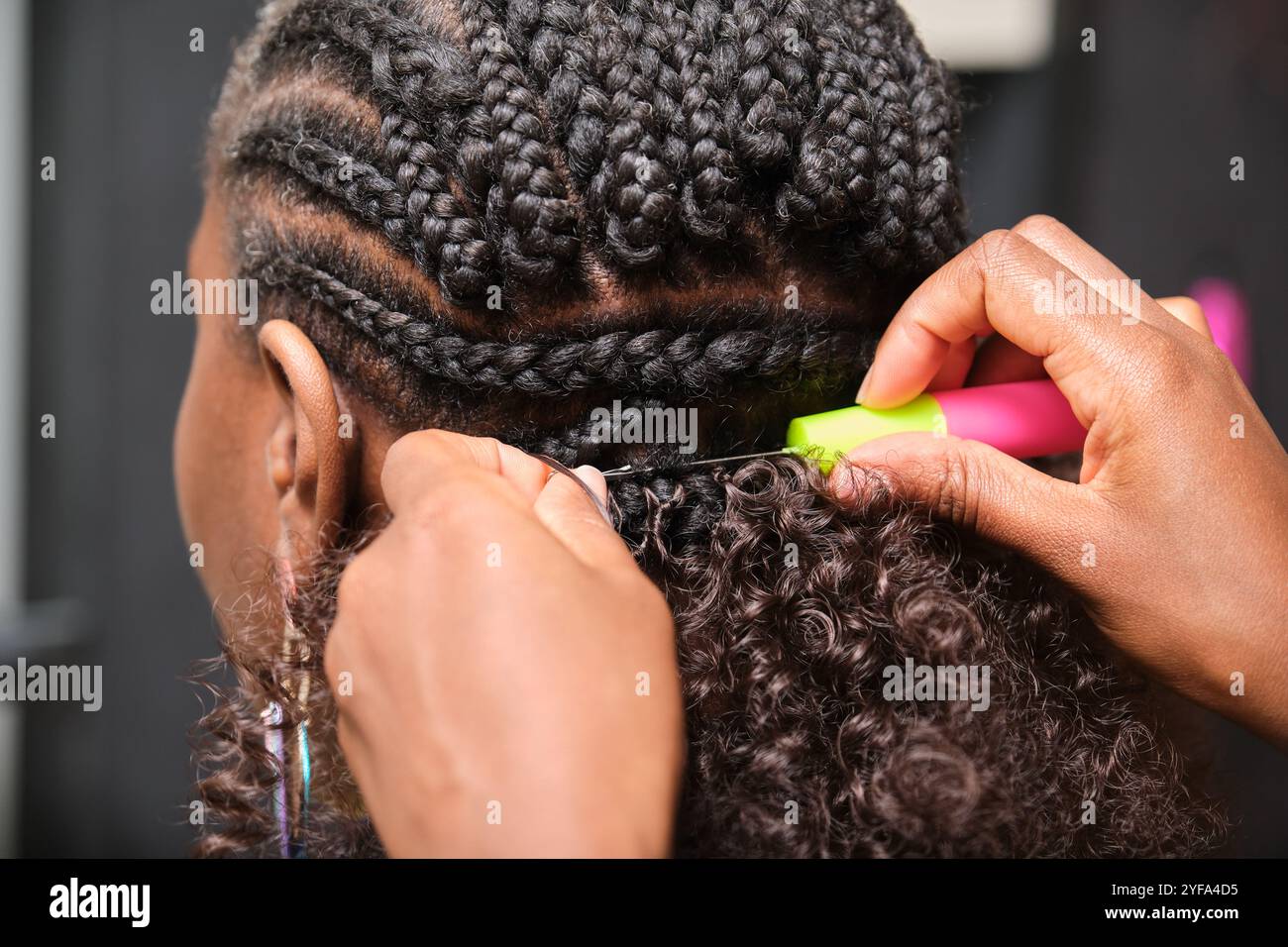 Parrucchiere che fa trecce all'uncinetto sul cliente con capelli afro Foto Stock