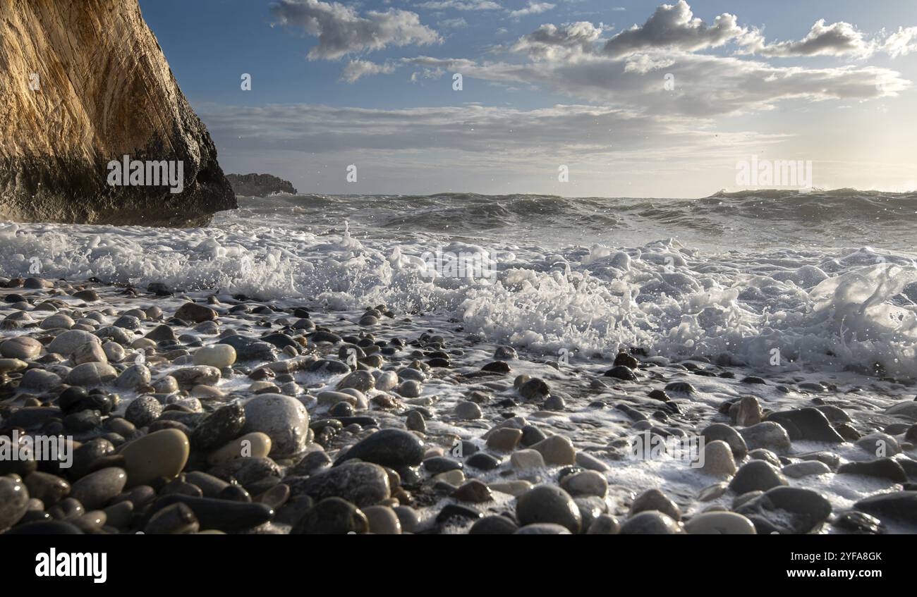 Vista ad angolo basso del paesaggio marino con onde ventose che spruzzano sulla roccia e sui ciottoli marini. Roccia di Afrodite a Paphos, Cipro, Europa Foto Stock