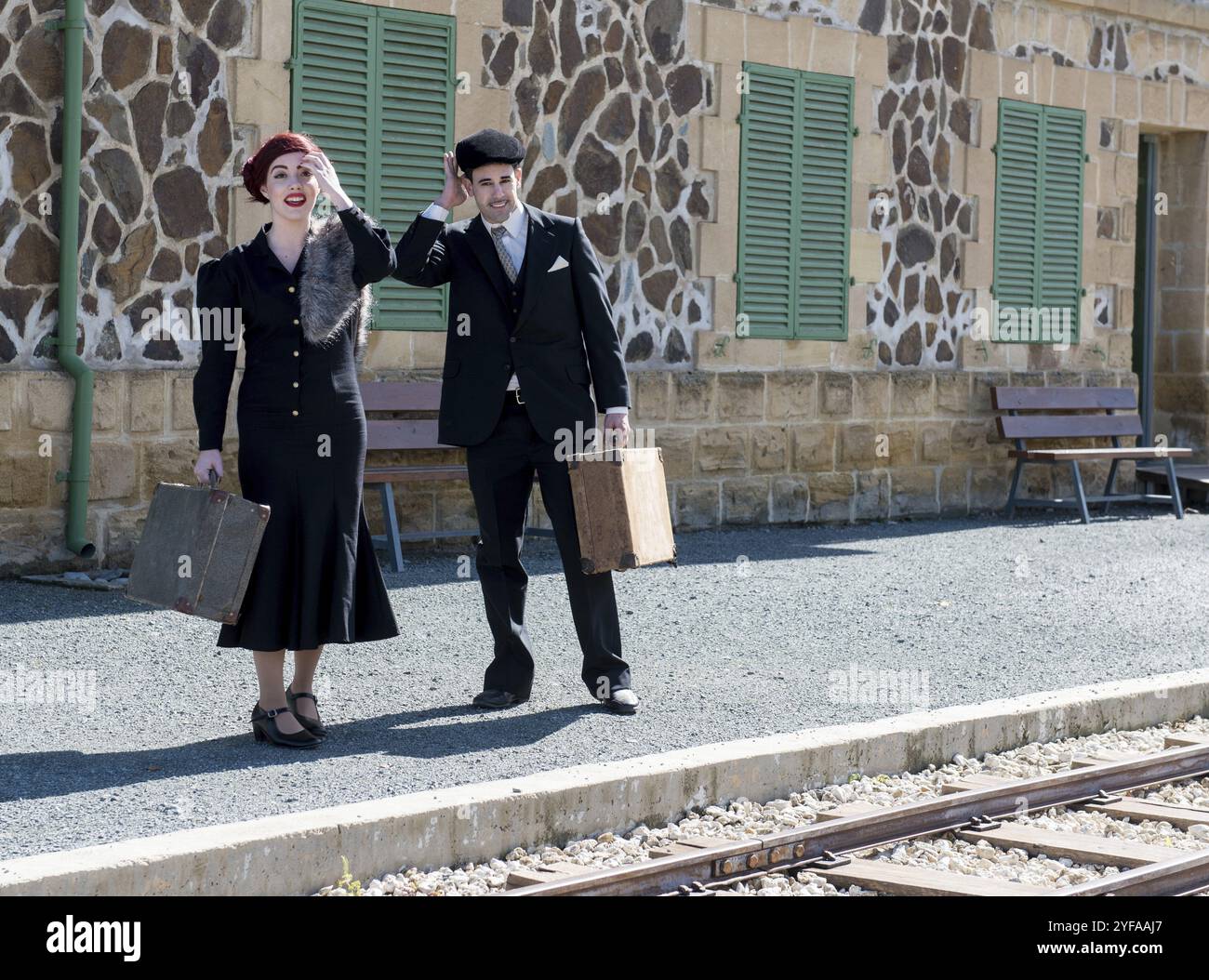 Giovane coppia con valigie d'epoca sulla stazione in attesa del treno per la partenza Foto Stock