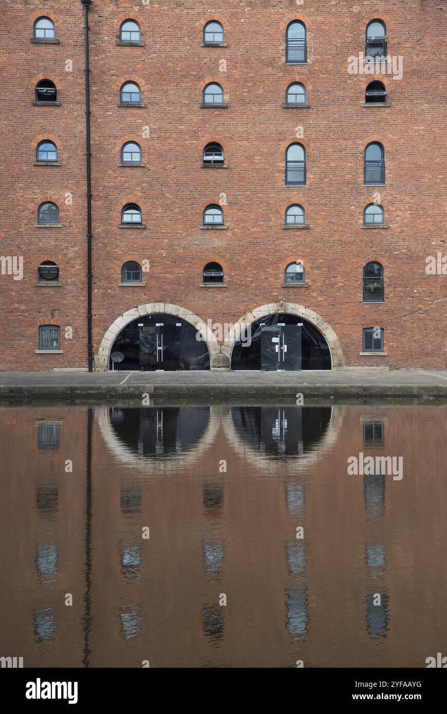 Edificio murale in pietra con finestre chiuse che si riflettono nell'acqua. Architettura simmetrica tradizionale. Manchester Regno Unito Foto Stock