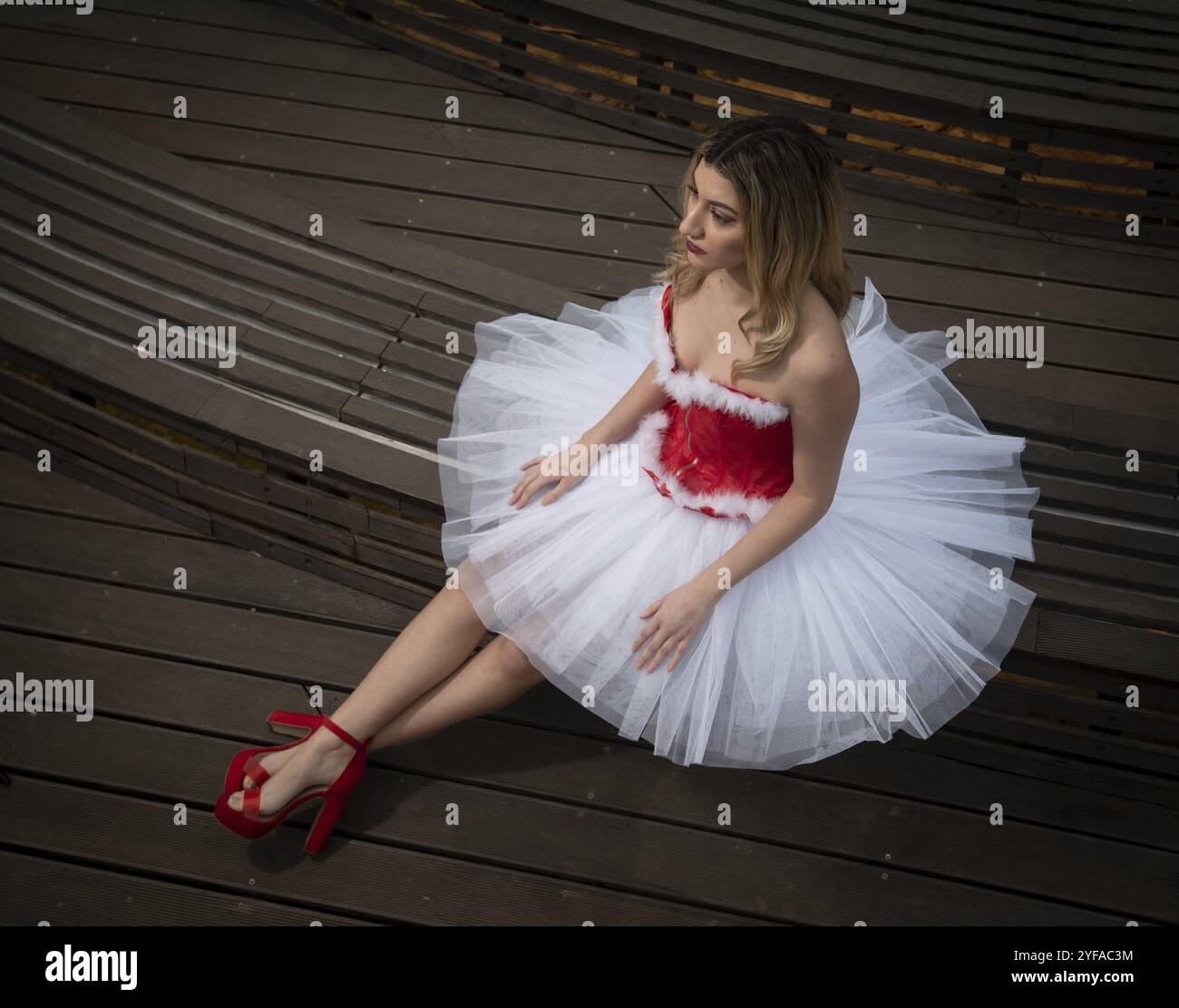 Ballerina con abito rosso bianco di natale in posa sul pavimento. Ballare all'aperto Foto Stock