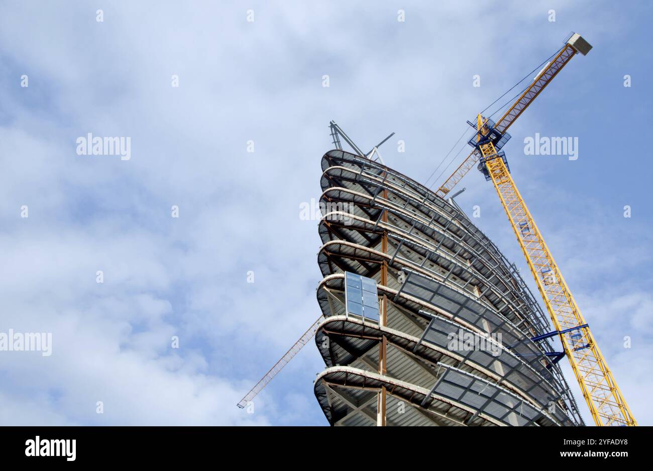 Moderna costruzione di grattacieli con gru gialla in una giornata di cielo azzurro Foto Stock