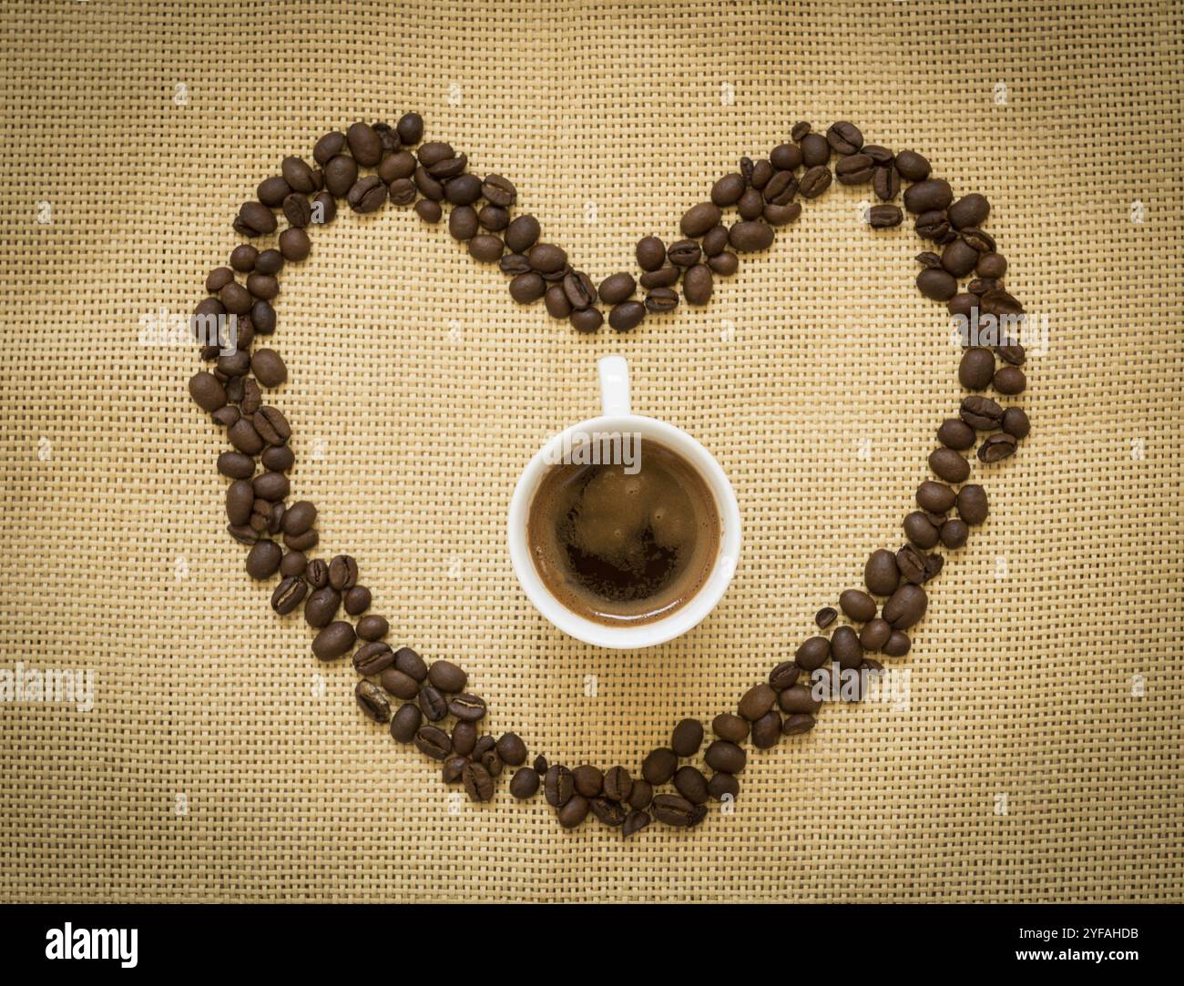 Chicchi di caffè a forma di simbolo del cuore e una tazza di caffè espresso nero. Concetto di "amo il caffè" Foto Stock