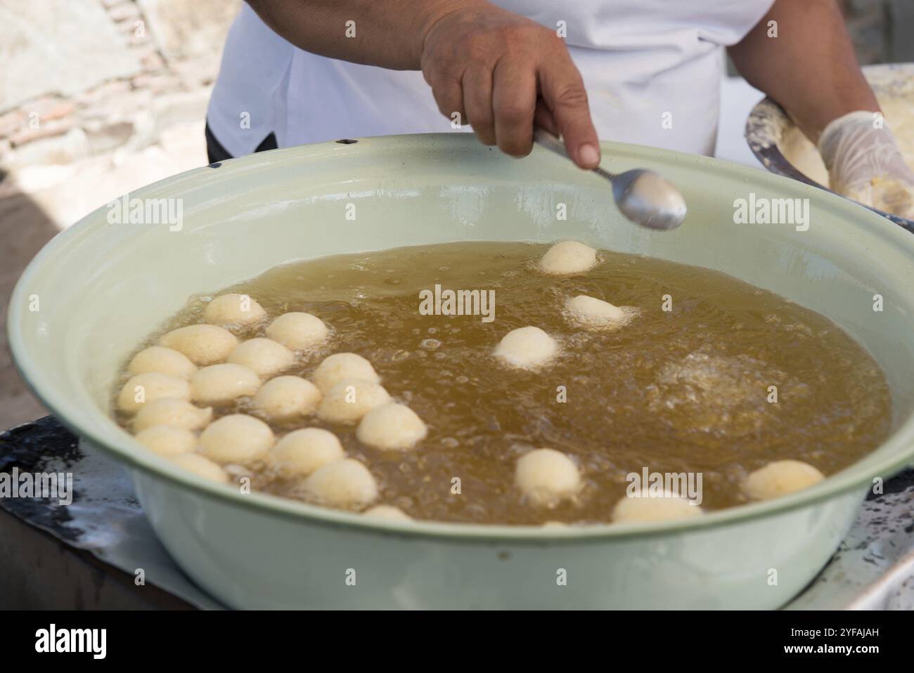 Donna che produce Loukoumades, una tradizionale pasticceria greca cipriota costituita da una palla di impasto fritta ricoperta di miele o zucchero Foto Stock