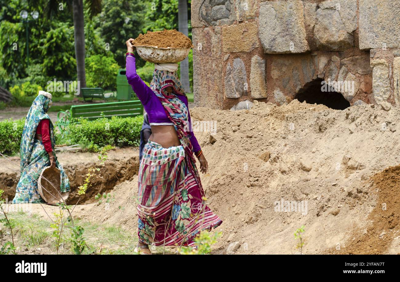 Nuova Delhi, India, 8 agosto 2018: Donne indiane che lavorano nell'industria edile all'aperto portando sabbia in testa per l'edilizia, Asia Foto Stock