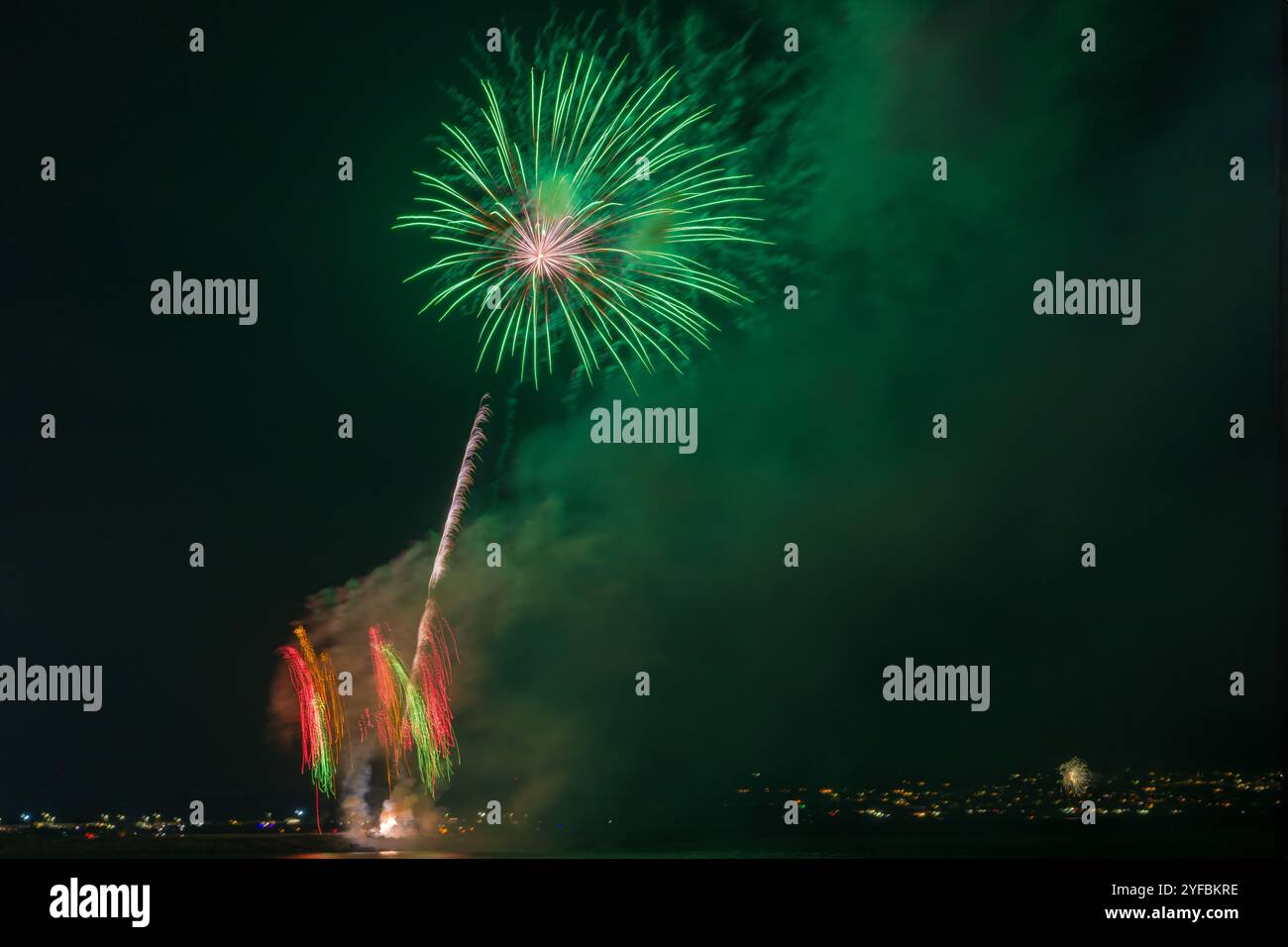 A Palm Shell Firework over Coney Beach, Porthcawl UK, con le luci di Ogmore-by-Sea sullo sfondo.2 novembre 2024. Foto Stock