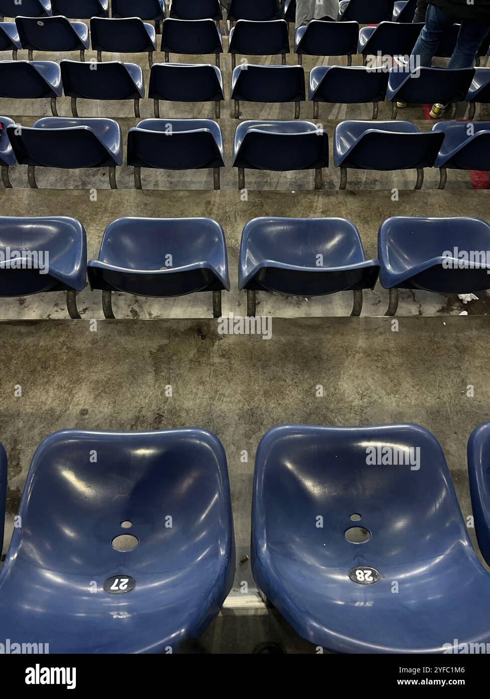 posti a sedere vuoti blu per lo stadio con adesivi numerati, per catturare un momento di tranquillità in un'arena altrimenti affollata Foto Stock