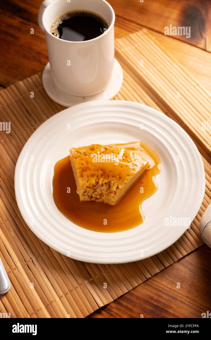 dessert con flan, ricetta semplice fatta in casa, nota anche come creme caramel, budino alla crema di caramello o crema pasticcera all'uovo, servito su un piatto bianco su un tavolo di legno. Foto Stock