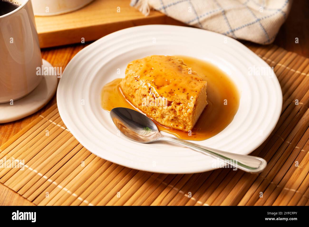 dessert con flan, ricetta semplice fatta in casa, nota anche come creme caramel, budino alla crema di caramello o crema pasticcera all'uovo, servito su un piatto bianco su un tavolo di legno. Foto Stock