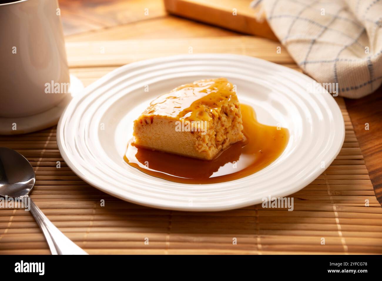 dessert con flan, ricetta semplice fatta in casa, nota anche come creme caramel, budino alla crema di caramello o crema pasticcera all'uovo, servito su un piatto bianco su un tavolo di legno. Foto Stock